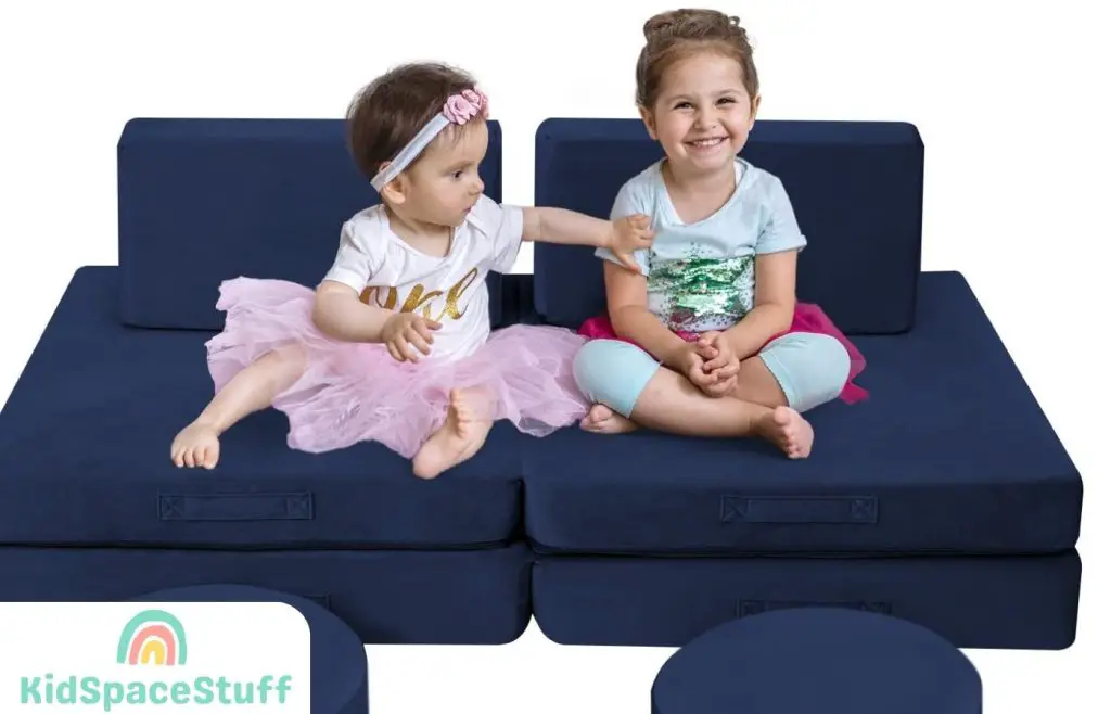A picture of two babies playing on the couch