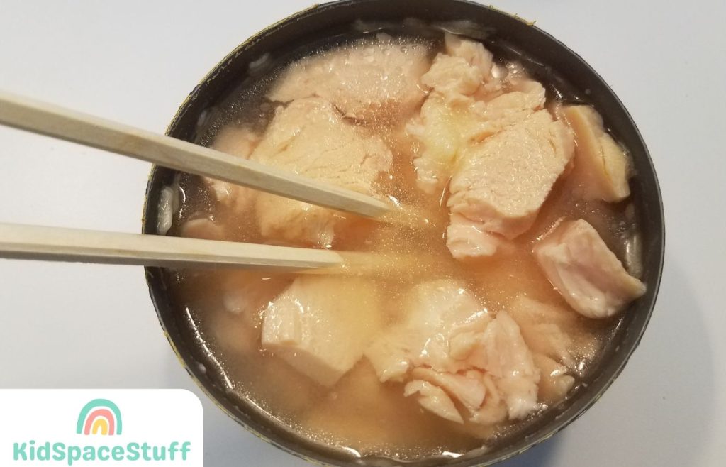 Open can of canned chicken with chopsticks