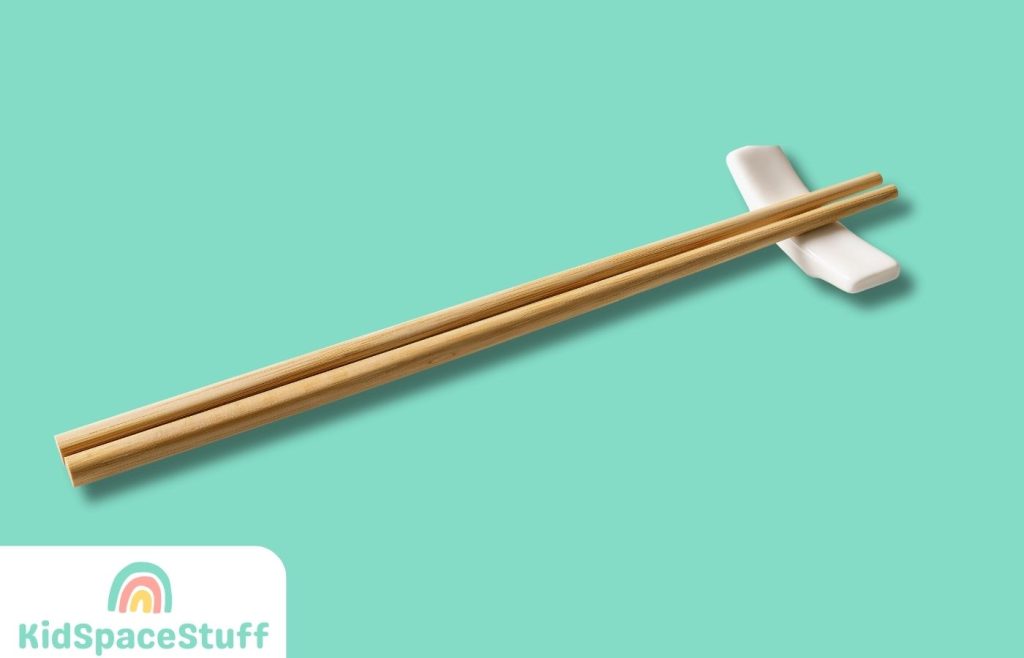 Wooden chopsticks on a white chopstick rest cutout.